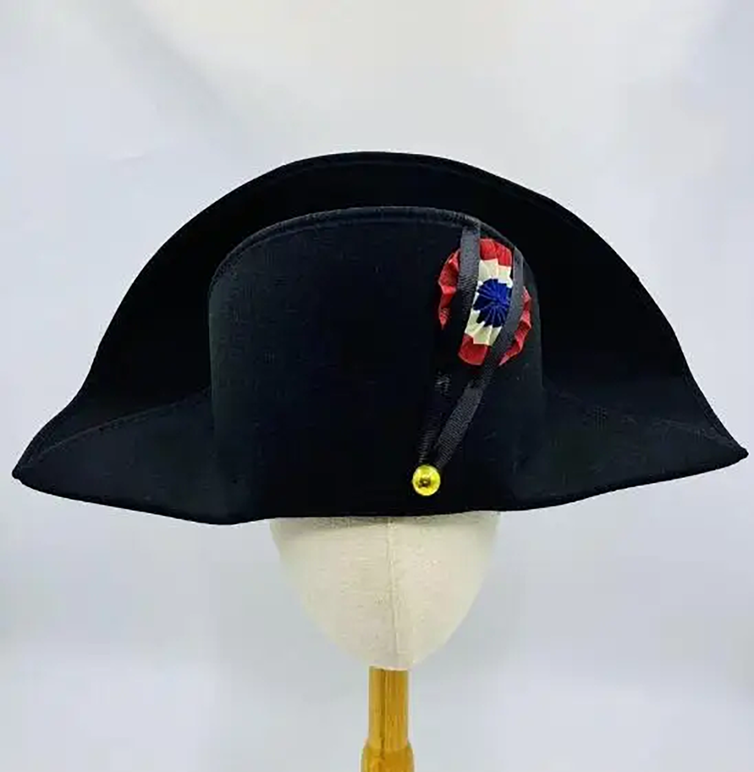 Black tricorn hat with decorative ribbon on a mannequin head against a white background