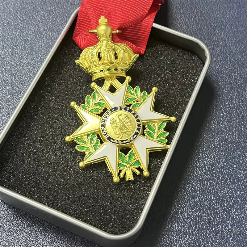 Decorative medal with gold and green design on a red ribbon, displayed in a box.