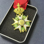 Decorative medal with gold and green design on a red ribbon, displayed in a box.