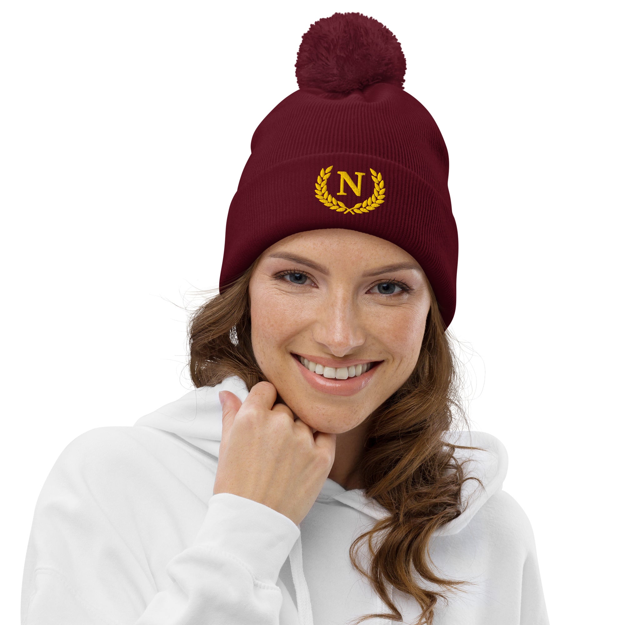 Woman wearing a maroon beanie with a yellow logo on a white background