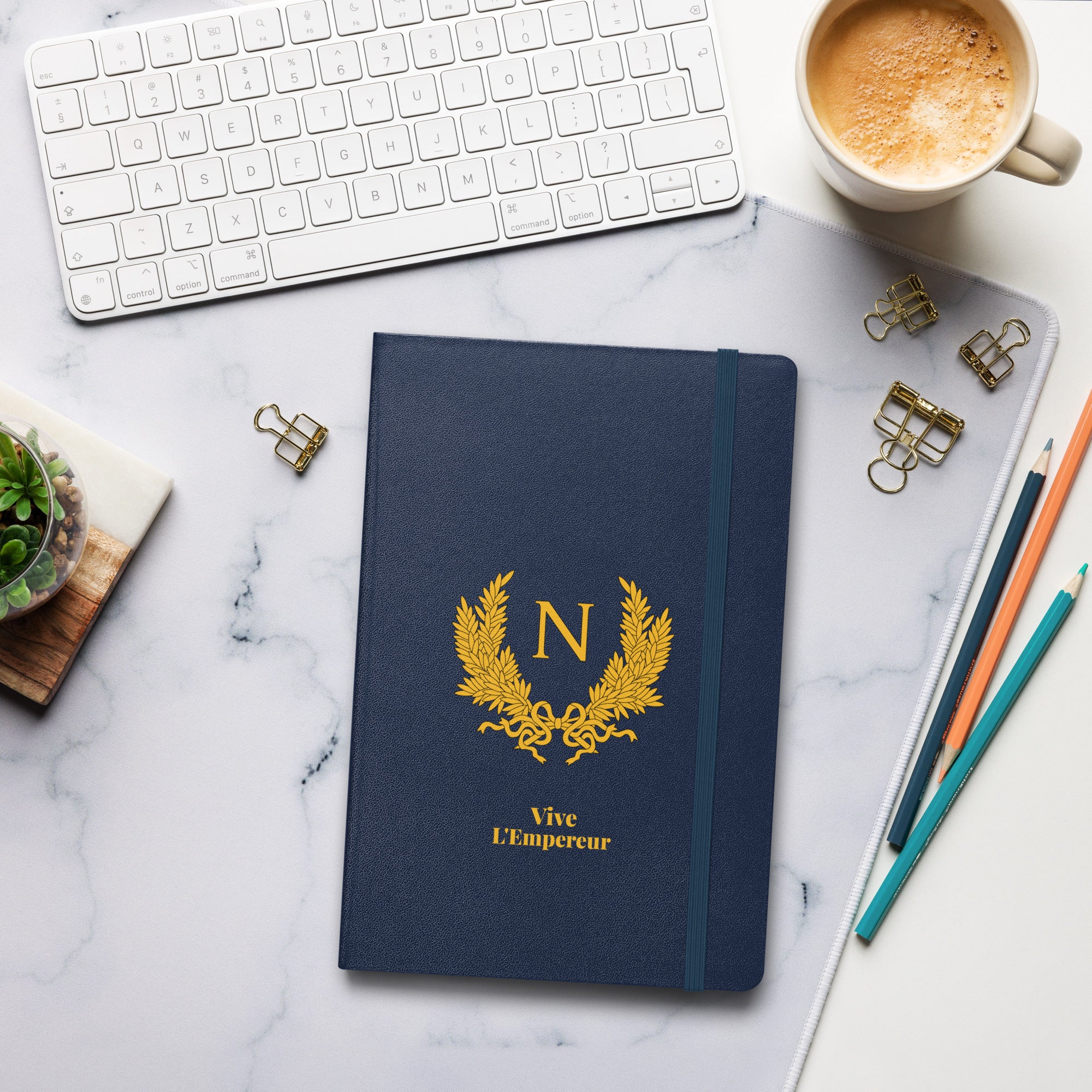 Blue notebook with gold emblem and text on a marble desk with office supplies